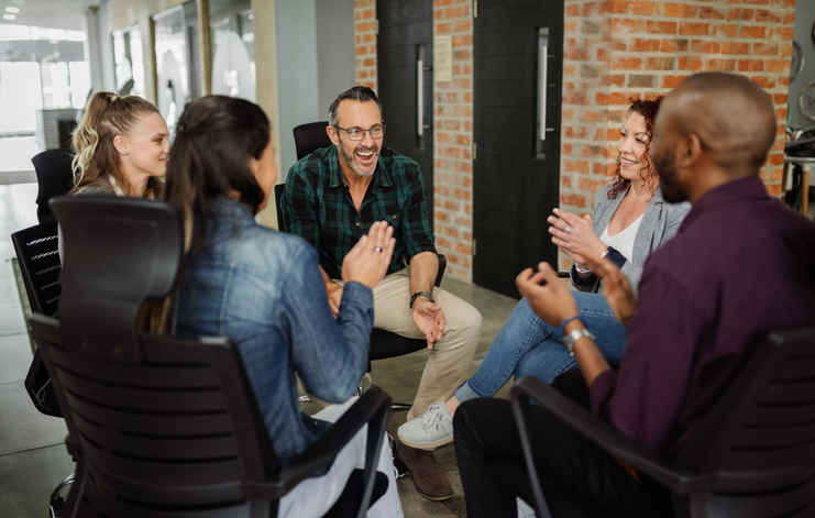 A diverse group of professional adults sitting around a table having a conversation